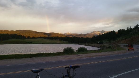A bike parked on the side of a road, a lake and mountains in the distance